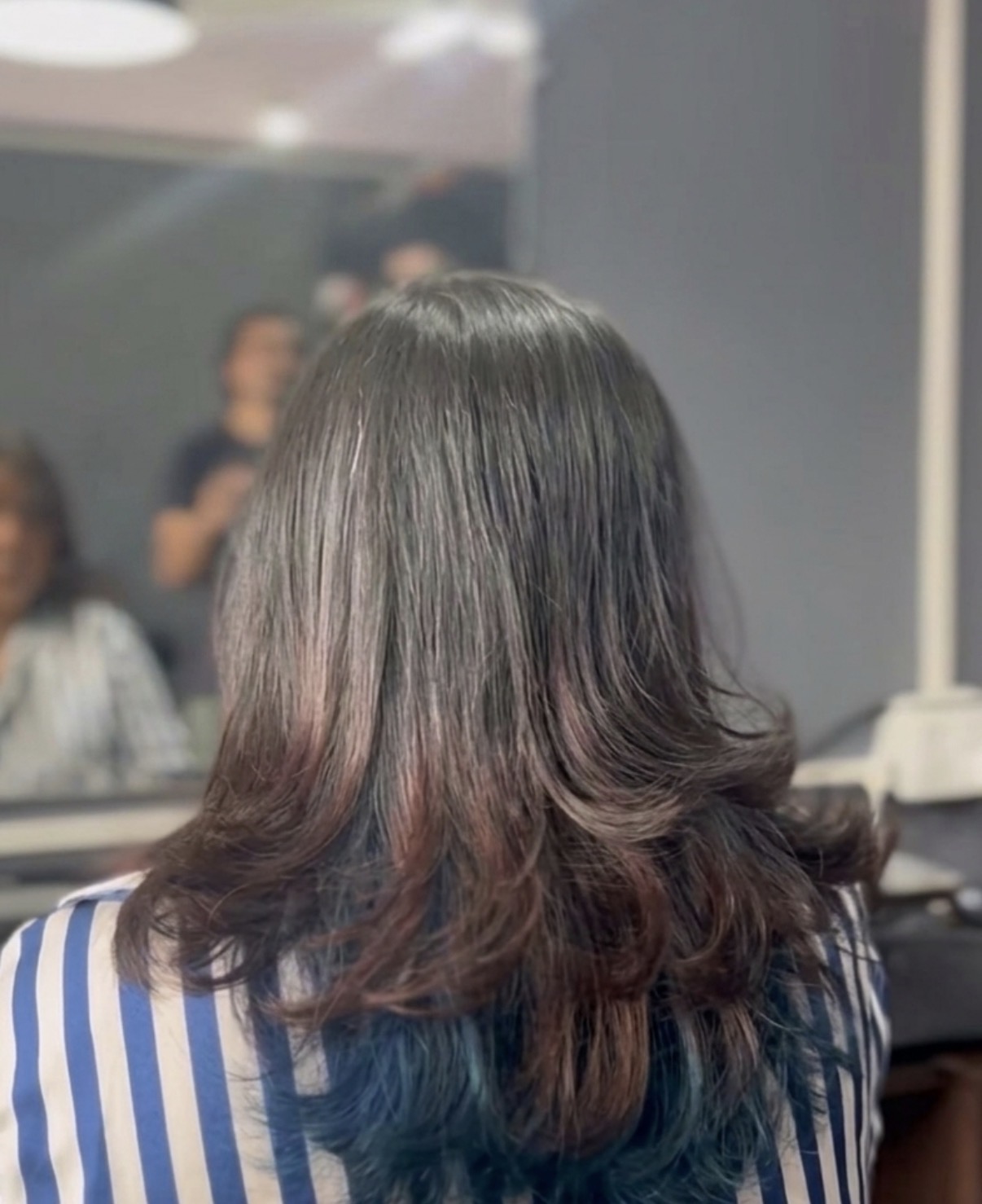 Back view of a soft layered women's haircut with flowing ends