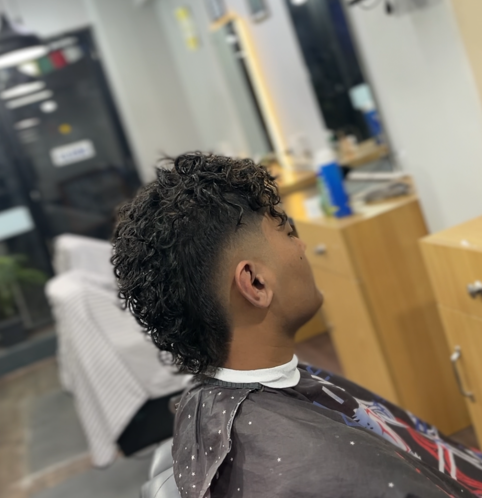 Side back view of a curly mullet haircut in the barber shop