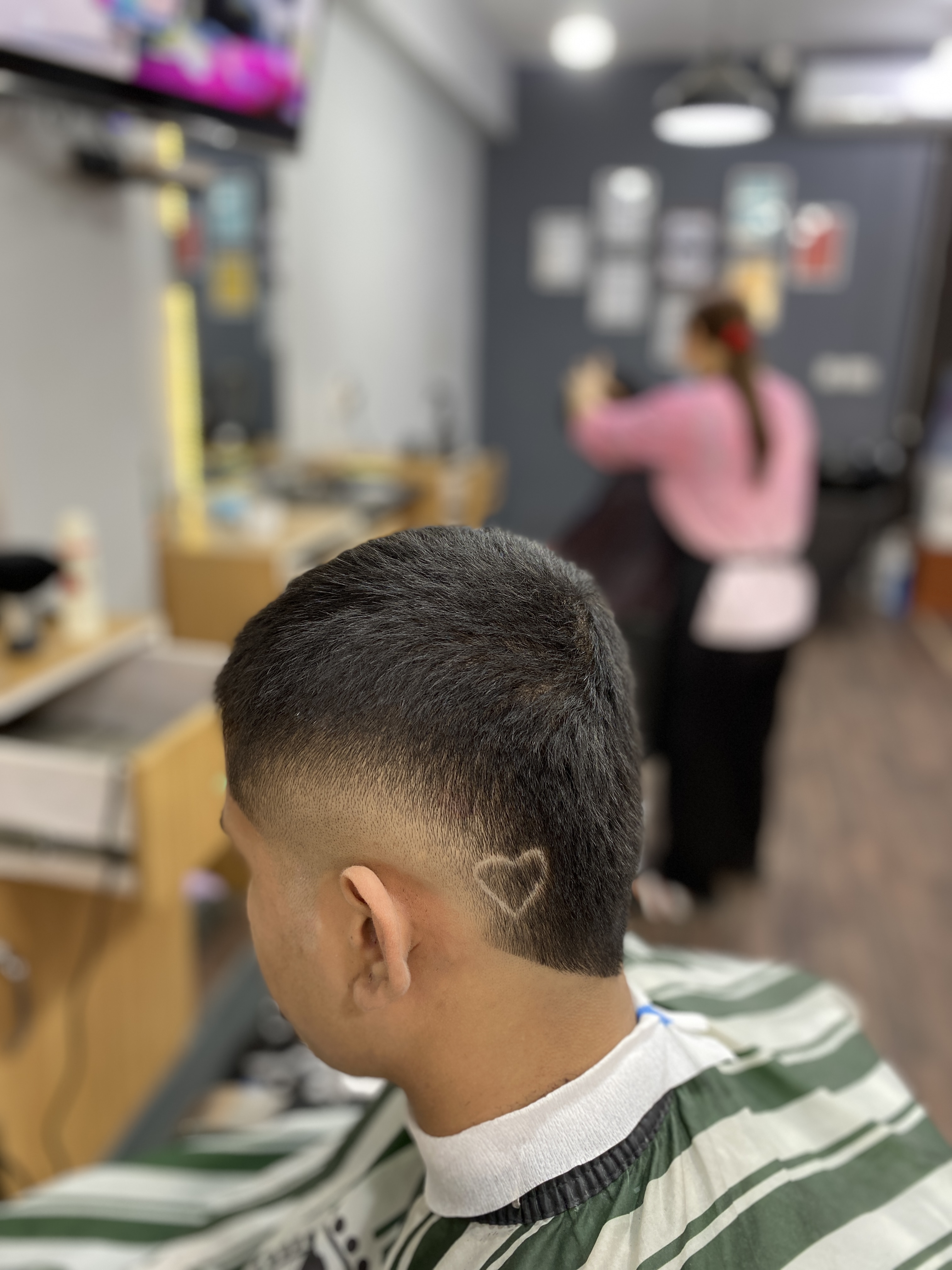 Side back view of a fade haircut with a heart design behind the ear
